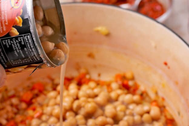 Chickpeas are poured from the can into a soup pot.