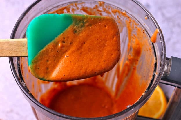 Chipotle salad dressing is mixed in a blender and tested with a spatula.