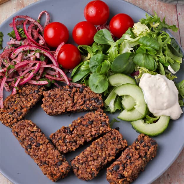 6 black bean koftas are placed on a blue plate.