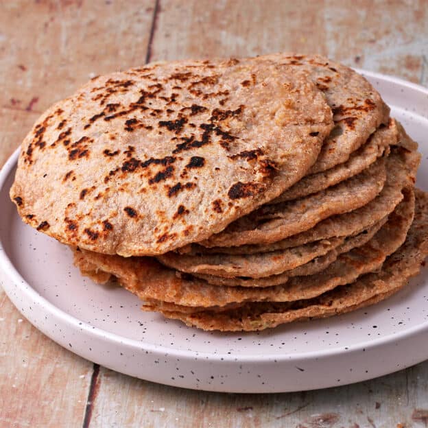 Golden whole wheat tortillas are stacked on a plate.