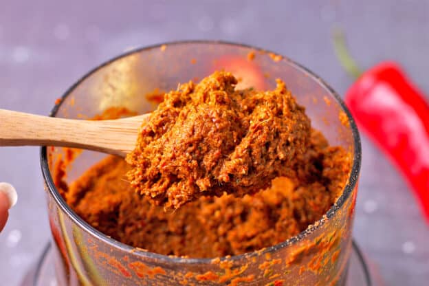 Thai red curry paste in spice grinder with spoon.