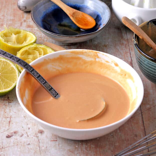A ladle in a bowl of tahini lime dressing.