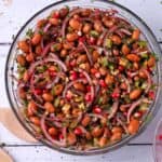 A bowl of Borlotti bean salad with red onions, celery, walnuts, and pomegranate arils.