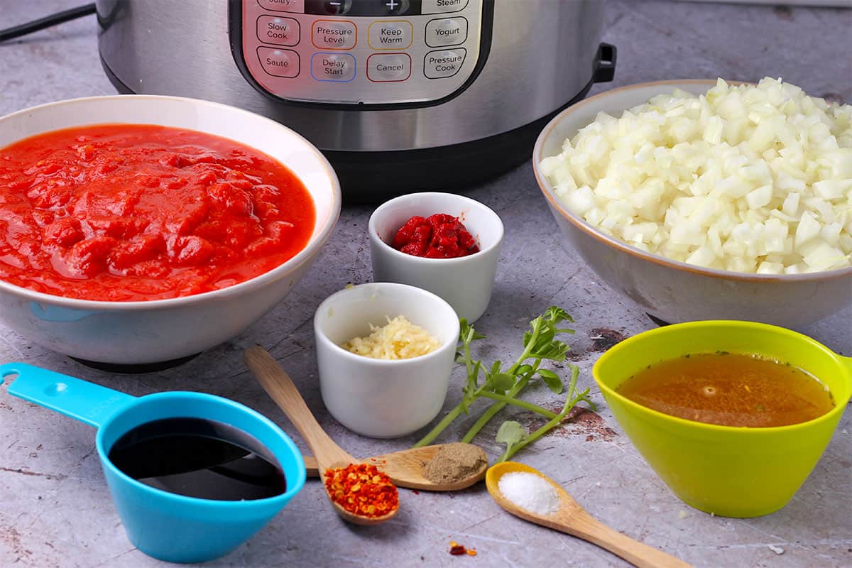 The ingredients for basic tomato sauce in cups and spoons.