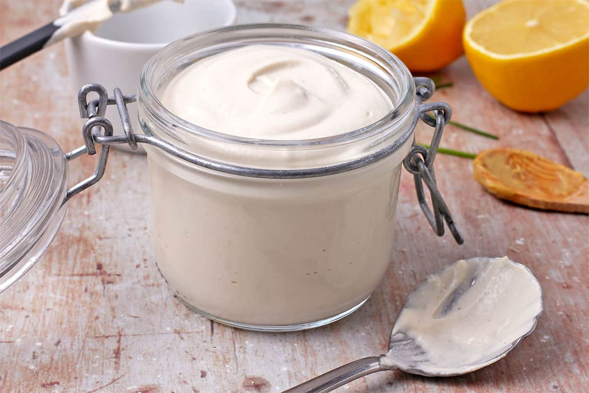 A jar with vegan mayo and a spoon beside it.