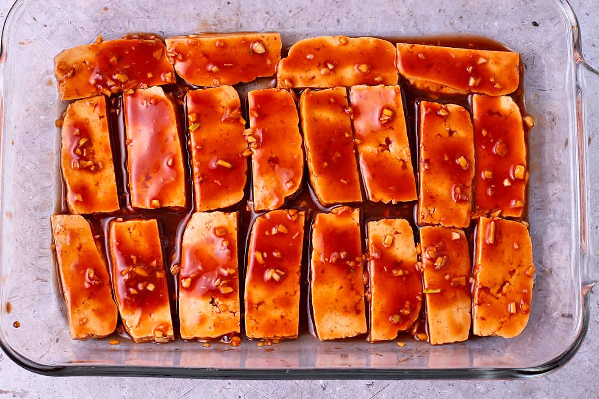Tofu is lined in a baking tray and covered with Huli Huli sauce.