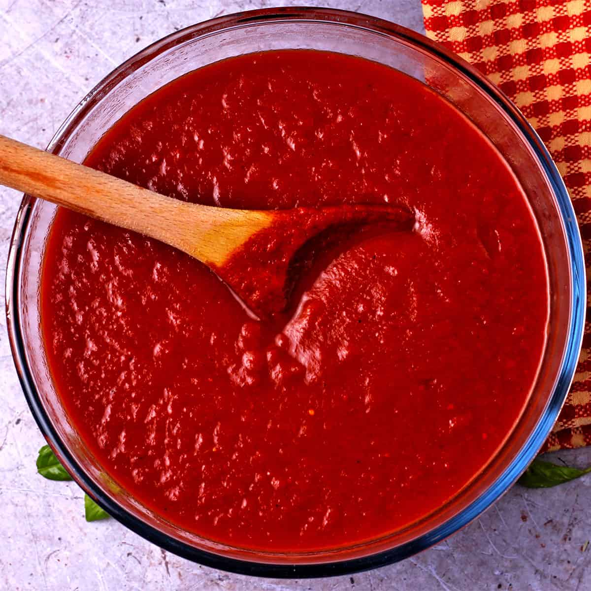 A glass bowl filled with tomato sauce.