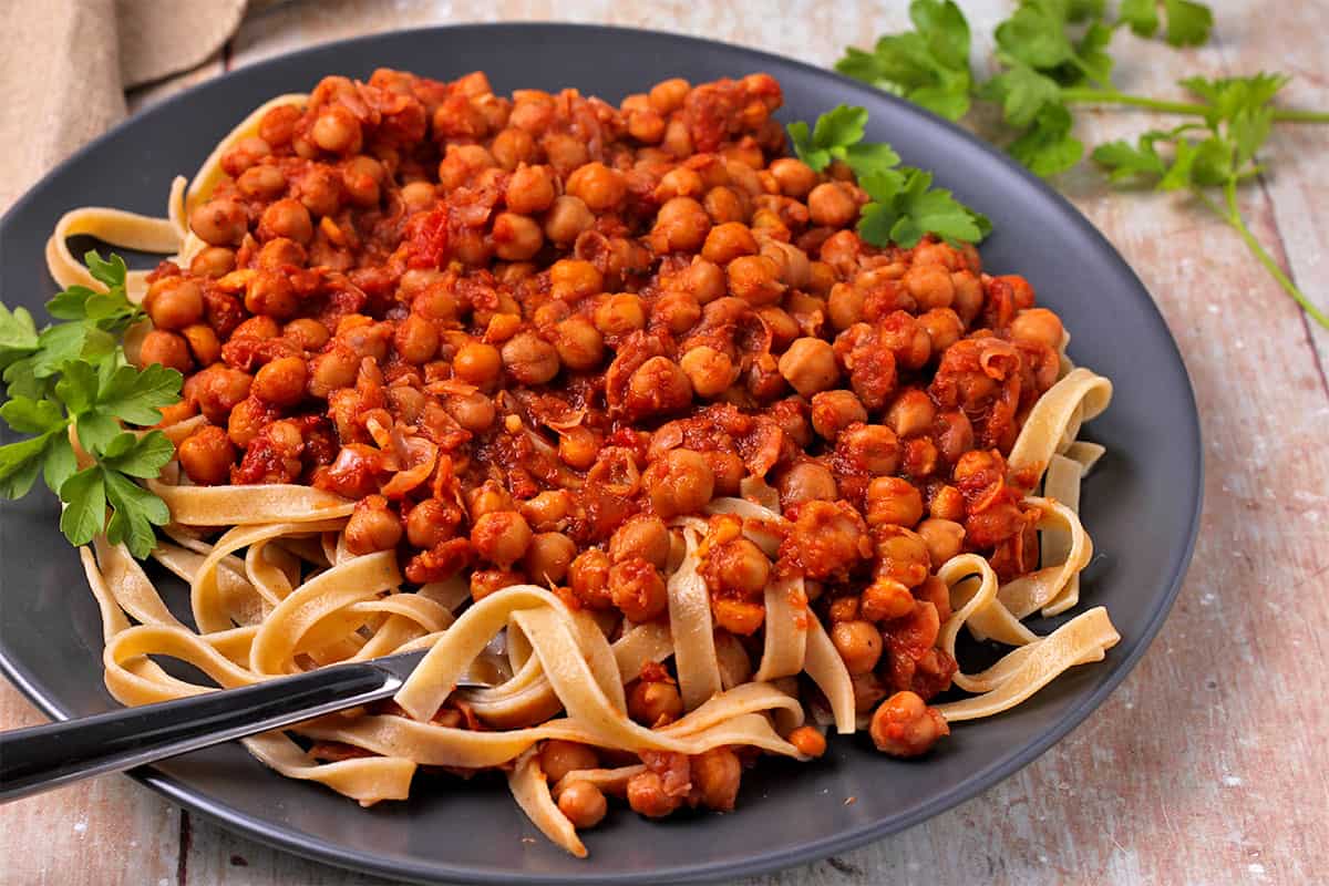 A plate with pasta topped with chickpeas Kapama.