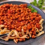 A plate of chickpeas in tomato sauce with pasta.