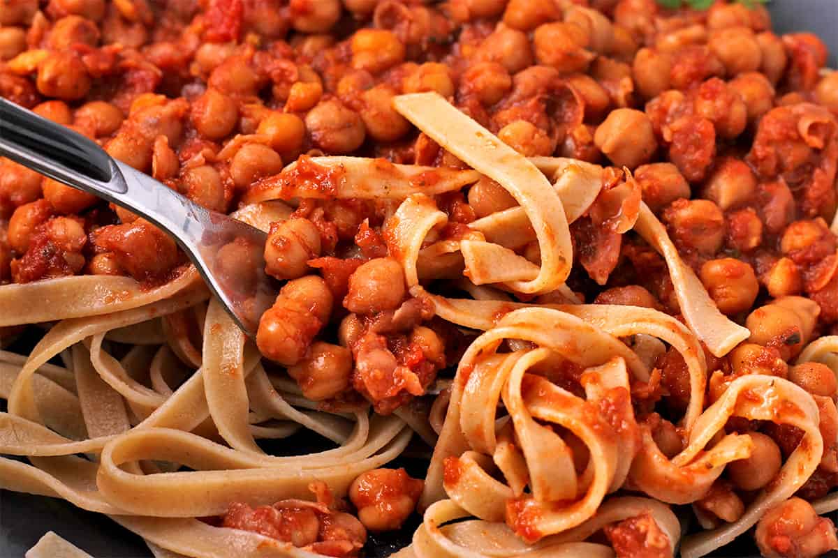 Pasta and chickpeas in tomato sauce a scooped up with a fork.