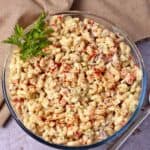 Curried vegan macaroni salad in a glass bowl with paprika on top.