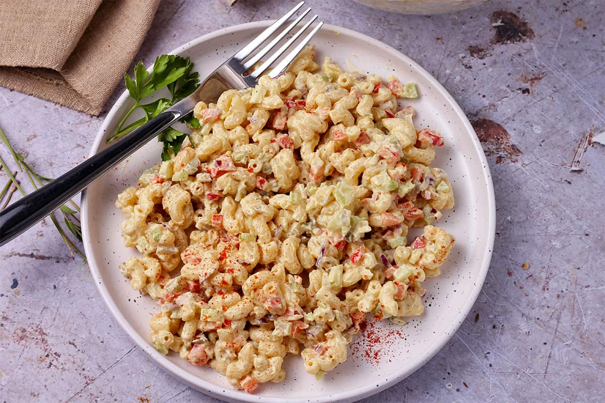 A plate of curried macaroni salad with a fork.