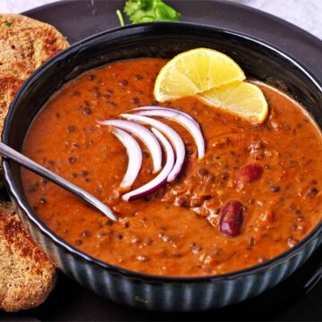 A bowl of vegan dal makhani with a spoon.
