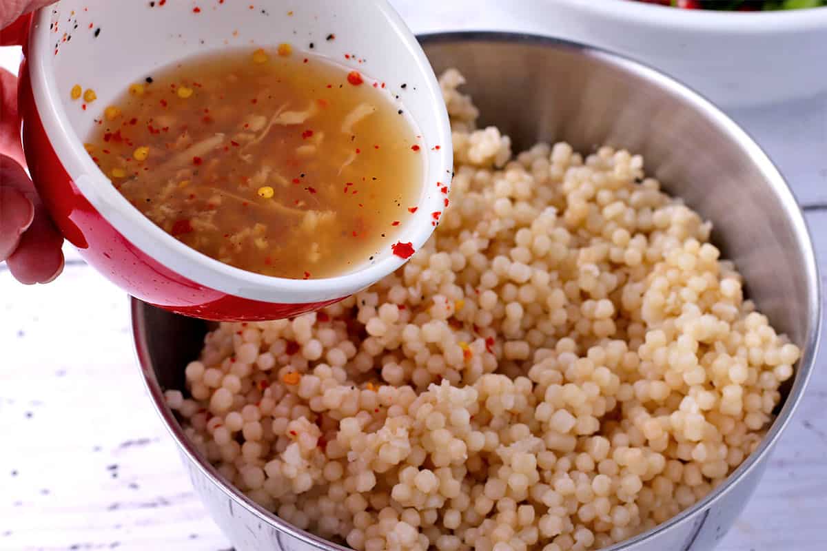 Lemon juice and chili flakes are poured over pearl couscous.