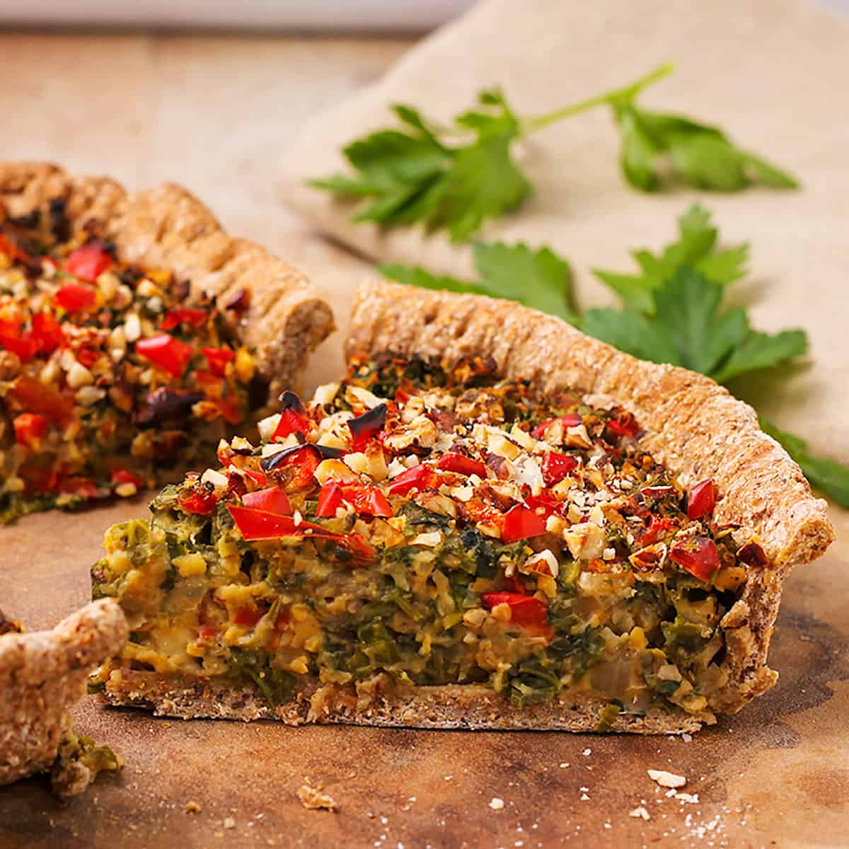 A piece of mushroom & kale quiche with diced red peppers and hazelnuts.