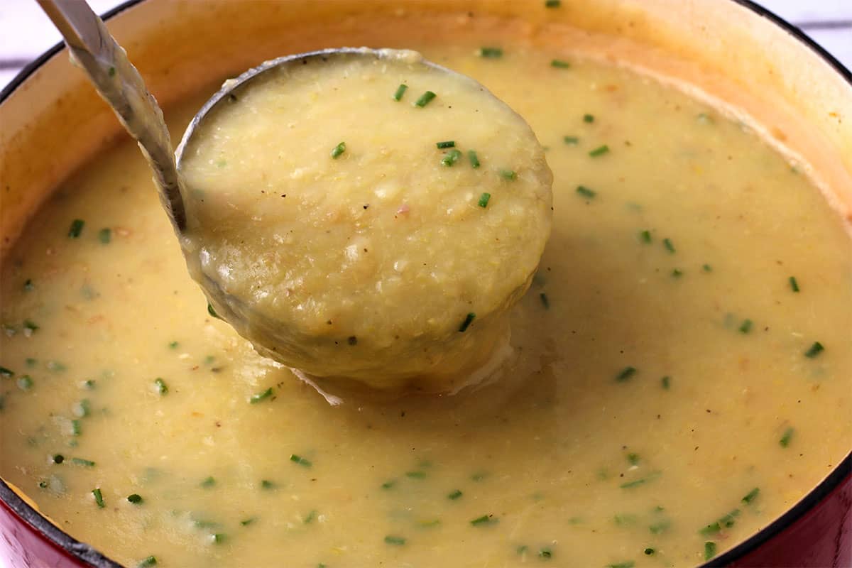 Potato leek soup in a pot with chopped chives.