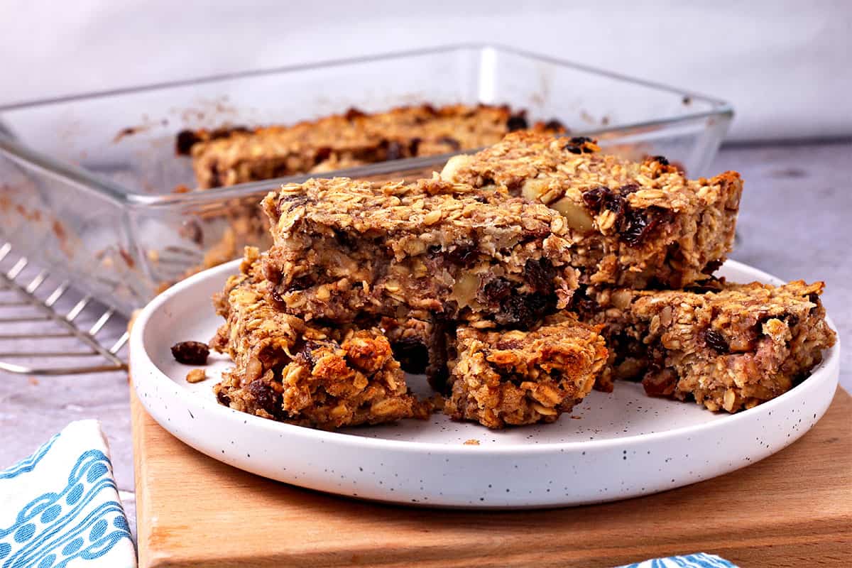 Oatmeal raisin bars are cut and stacked on a white plate.