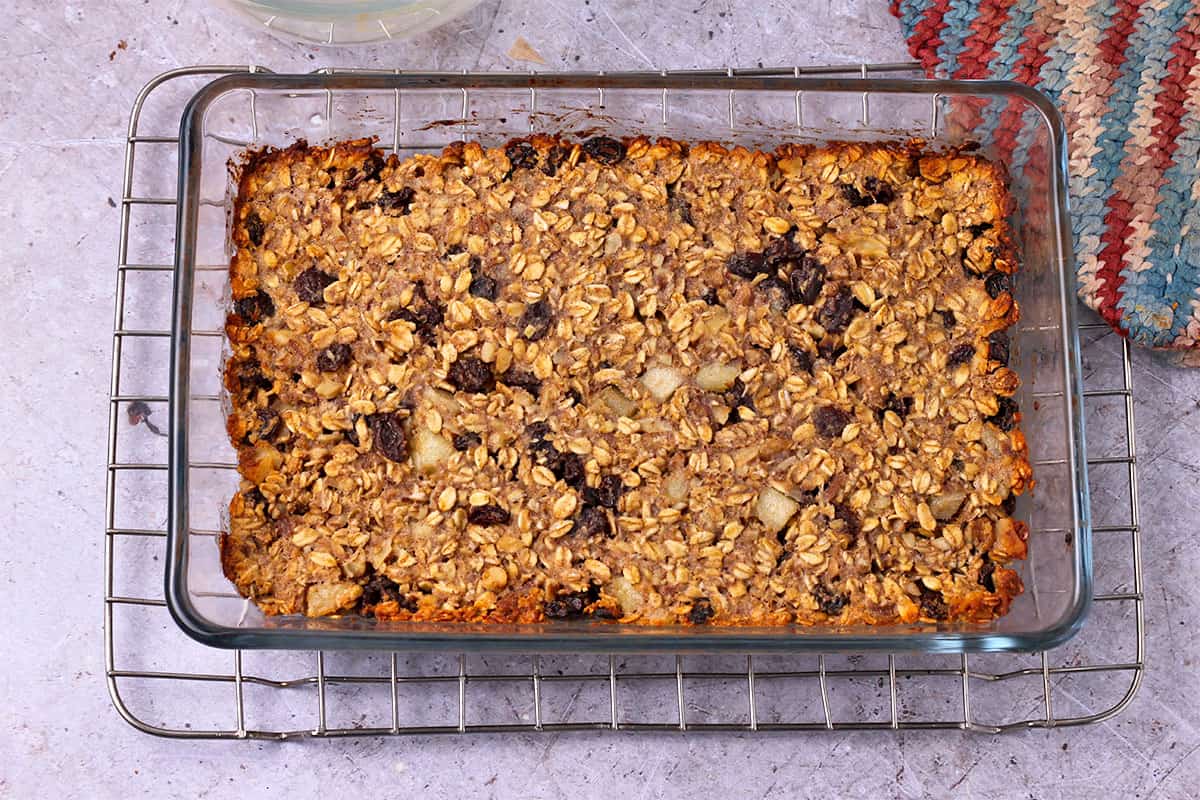 A glass baking dish with oatmeal raisin bars set on a wire rack.